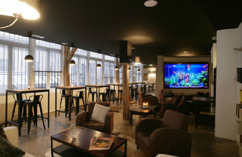 Écran Aquamovie encastré dans le mur d'un bar-lounge avec fauteuils et tables hautes