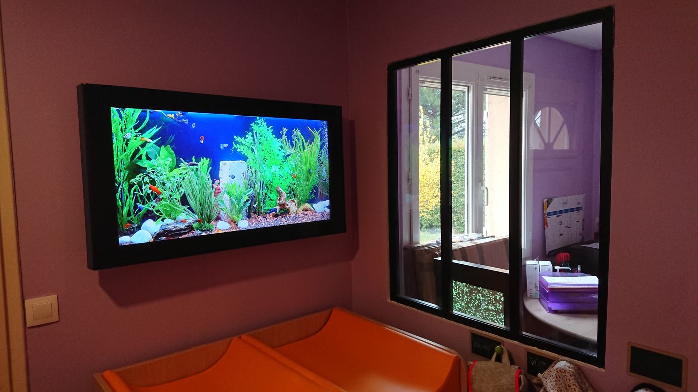 Écran Aquamovie cadre noir au-dessus des tables à langer d'une crèche